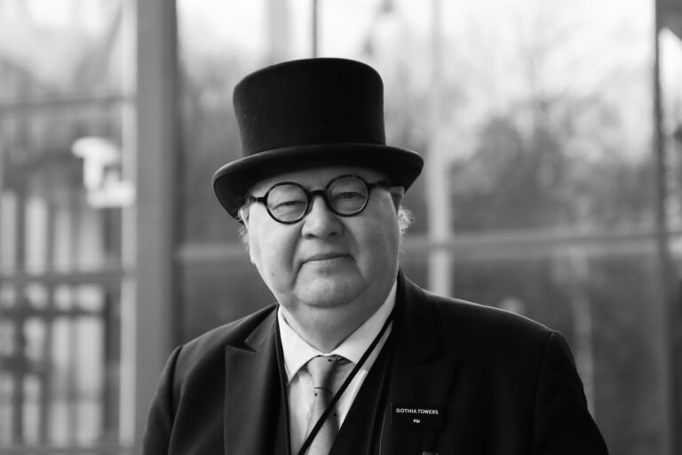 Black and white portrait of an elderly gentleman in Gothenburg wearing a hat and glasses.
