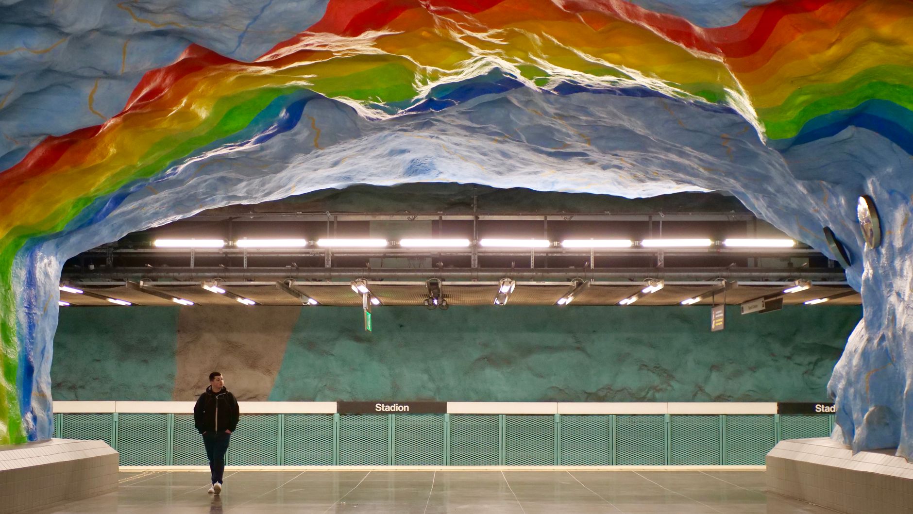 A vibrant view of the Stadion metro station with rainbow art in Stockholm.