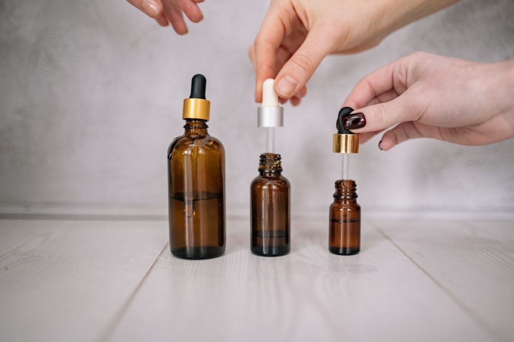 Close-up shot of hands holding brown bottles with droppers, ideal for skincare and aromatherapy themes.